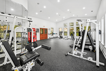 a gym with weights and cardio equipment on the floor and a window
